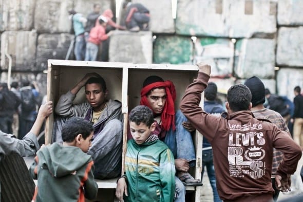 EGYPT. Cairo. January 2013. Young protestors take shelter behind a barricade during clashes with Egyptian police on the second anniversary of the Revolution by Moises Saman