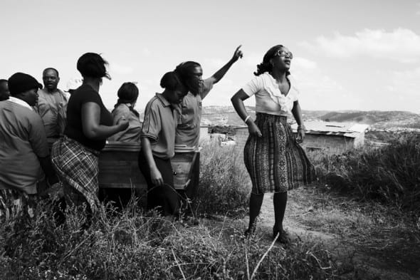 Thabsile Brightness Sishi, 25 (right), leads the funeral procession for her aunt Thembi Veze, along with her brother, Bongumenzi Knowledge Sishi, 15. Thabsile and Bongumenzi have been living with their aunt and her three children in the Richmond Farm Transit Camp near Durban since 2009.  “In the camp, I can’t say it’s nice to stay here– there’s no park, nowhere to play soccer, nowhere to rest,” says Bongumenzi. “It’s too dangerous. There’s no security. We are waiting for moving – they are still building the RDPs. They said we would be here two  years.” by Krisanne Johnson. South Africa's Post-Apartheid Youth 