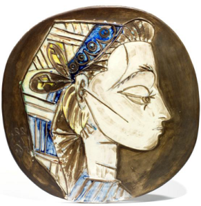 PABLO PICASSO (1881-1973) PORTRAIT DE JACQUELINE Exemplaire unique en terre de faïence blanche. Décor à l’engobe et émail sous couverte partielle au pinceau, patine noire, vert, blanc, bleue et jaune. Inscrit "Madoura empreinte originale, Picasso". Diamètre : 42 cm Estimation : 20 000/30 000 € Vendu: 183 000 €*