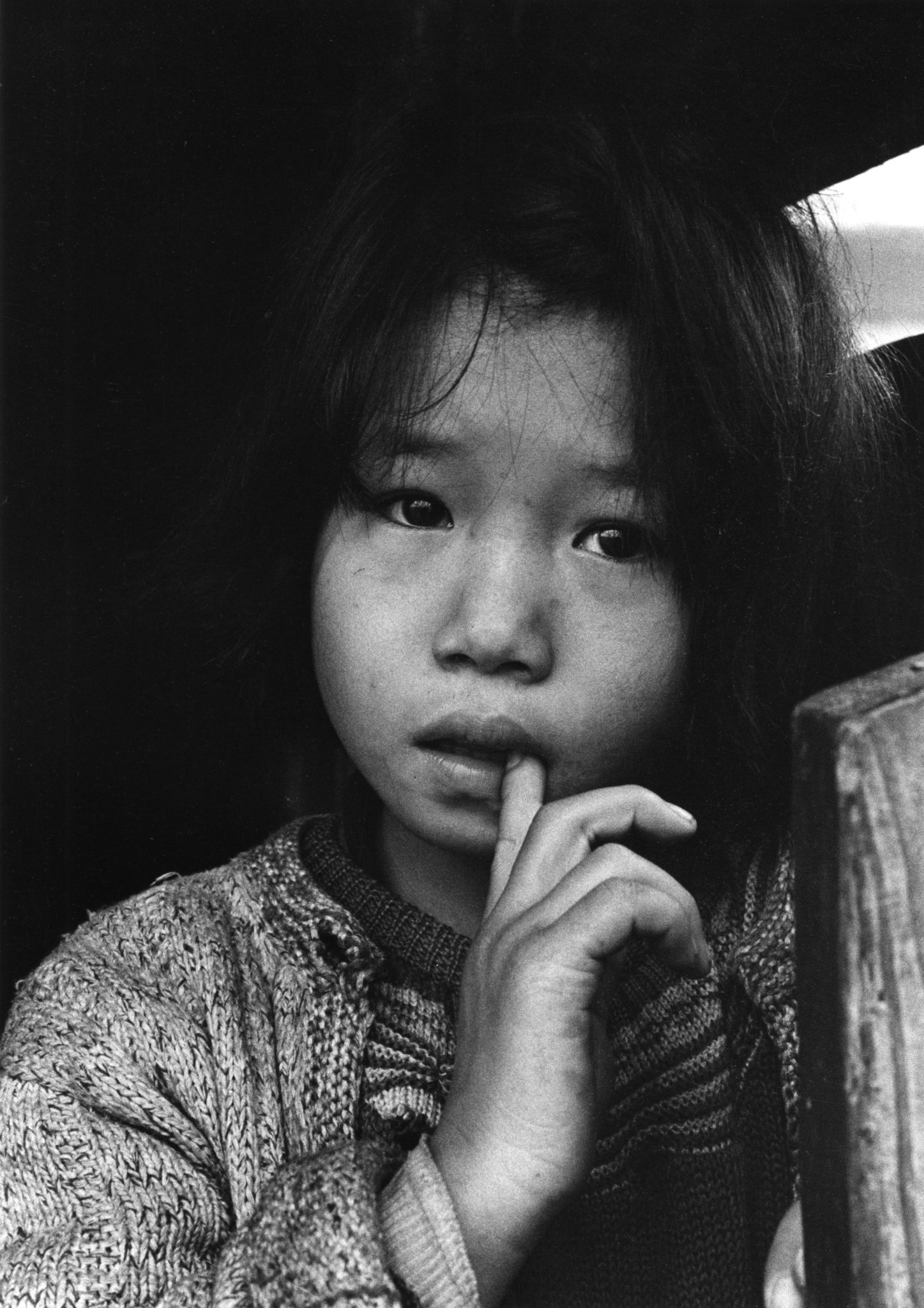 Photo en Noir et Blanc d'une jeune fille japonaise à l'air triste portant son index à la bouche