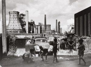 Rudolf Holtappel (Münster, Germania, 1923 – Duisburg, Germania, 2013) Duisburg Bruckhausen, Ebertstrasse con stabilimento metallurgico August Thyssen, 1959 mostra MAST bologna
