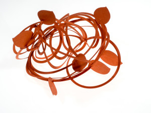 Maria Teresa Illuminato, bracciale Nest Nest, il nido è un bracciale di carta composto da una spirale lunga 4 metri, innestata da 7 foglie, da avvolgere attorno al braccio. Una corsa dentro al cuore. Un viaggio nella spirale della natura e della cultura della sostenibilità ambientale. Con lo scopo esplicito di promuovere una più efficace pratica di comportamenti virtuosi che inducano un cambiamento reale nelle abitudini quotidiane delle nostre società moderne.