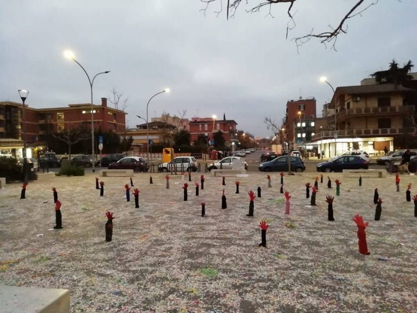 decine di mani di cartone invocano aiuto dall'asfalto