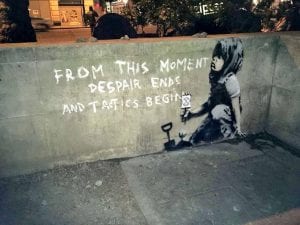bambino che semina una piantina in un murale attribuito a banksy