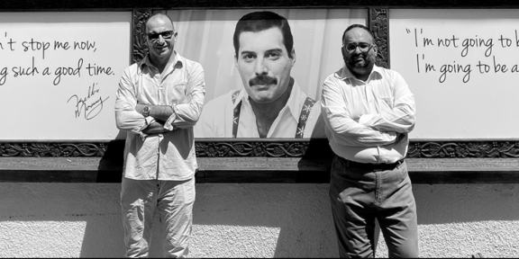 Due imprenditori posano davanti al Freddie Mercury Museum e sullo sfondo il volto del cantante