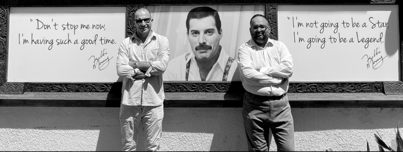 Due imprenditori posano davanti al Freddie Mercury Museum e sullo sfondo il volto del cantante