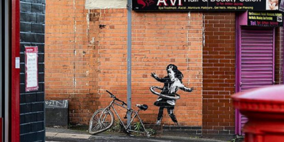 Murale di Banksy a Nottingham raffigurante una bambina che gioca con l'hula hoop con la ruota di una bicicletta