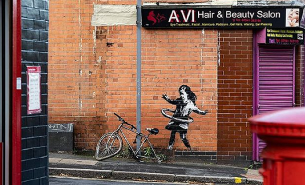 Murale di Banksy a Nottingham raffigurante una bambina che gioca con l'hula hoop con la ruota di una bicicletta