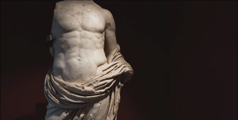 Statua in marmo locale di Vezza d’Oglio (alta Valle Camonica) raffigurante un personaggio maschile ritratto in posa eroica (part.), forse un giovane principe della famiglia imperiale. Datata ad età giulio-claudia, proviene dall’area del foro dell’antica Civitas Camunnorum. I-II d.C..