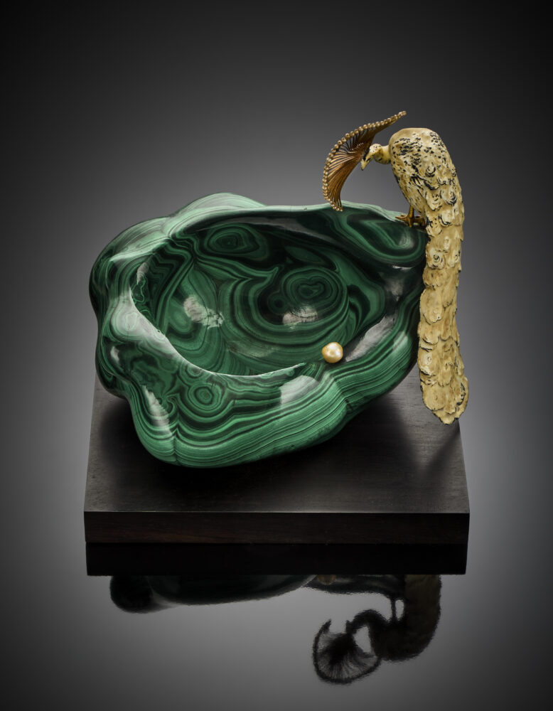 Lotto 131 Alfredo Ravasco, Coppa in malachite su base di legno ebanizzato con pavone in argento cesellato e smaltato con microperle sulla cresta, una perla leggermente irregolare a rifinire, h cm 15,50 circa g 2536 circa. In scatola originale Giacomo Ravasco. Valutazione € 7.000 - 12.000