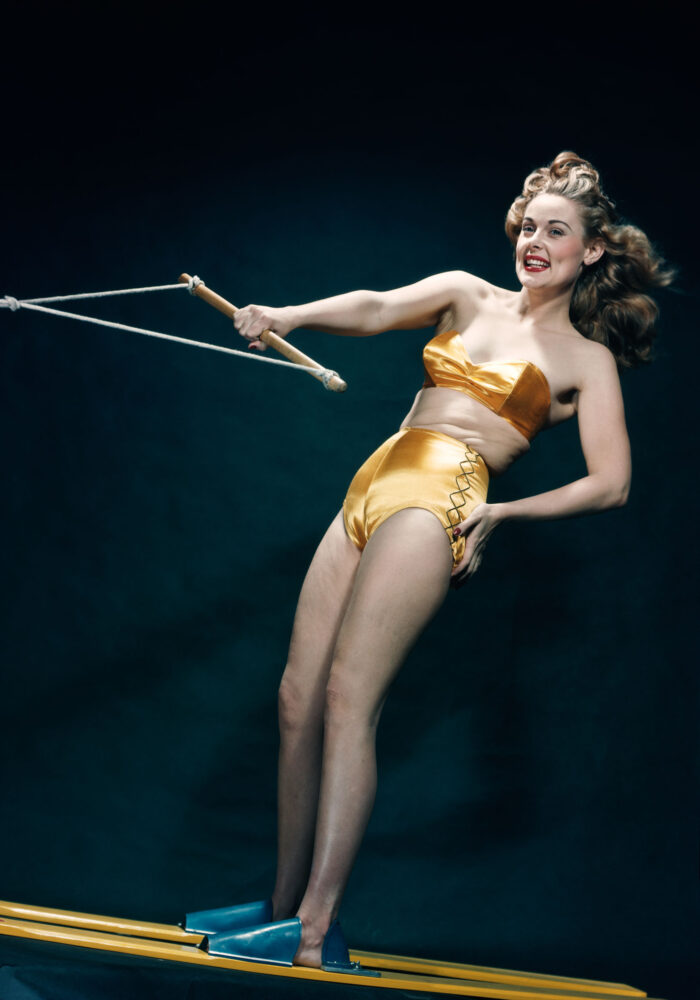 Let's Go Water Skiing - Smiling woman pinup wearing two piece gold bikini bathing suit posing riding water skis indoors, Los Angeles, California, 1949. (Photo by Camerique/Getty Images)