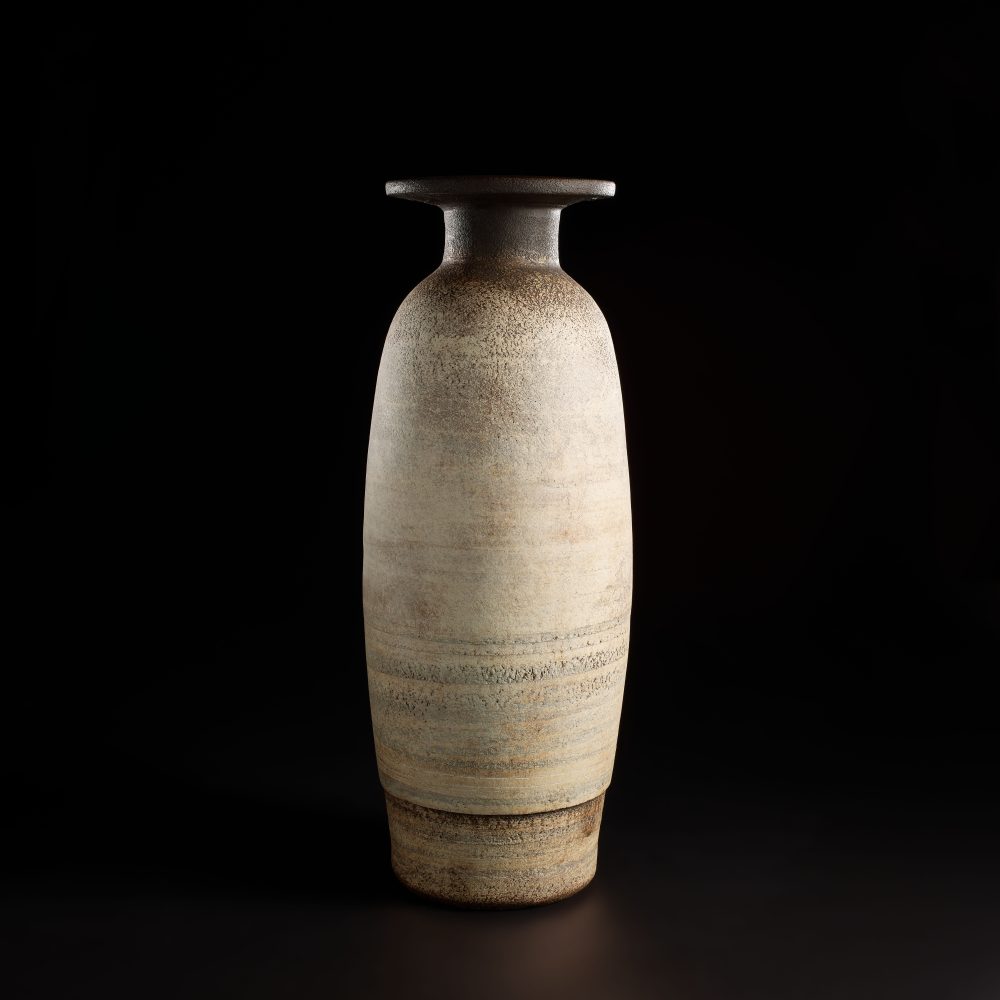 HANS COPER 1920 - 1981 Monumental bottle with disc top circa 1959 Stoneware, layered porcelain slips and engobes over a textured body, the neck, disc top lip and interior with a manganese glaze. 66 cm (25 7/8 in.) high ESTIMATE £120,000 - 180,000