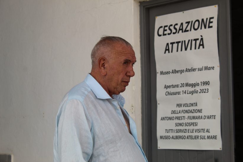 Antonio Presti difronte al cartello che annuncia la Cessazione dell'attività del museo albergo Atelier sul Mare. Foto Valentina Bracaforte