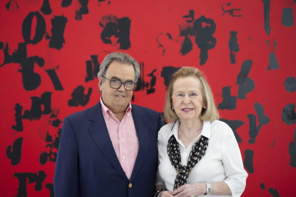 Portrait of Rosa and Carlos de la Cruz with Glenn Ligon's Debris Field (Red) # 3 (2018). Courtesy of the de la Cruz Collection.