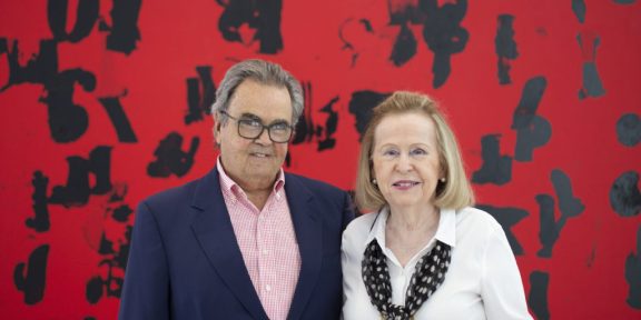 Portrait of Rosa and Carlos de la Cruz with Glenn Ligon's Debris Field (Red) # 3 (2018). Courtesy of the de la Cruz Collection.