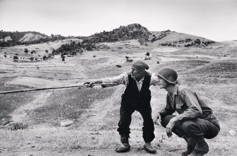 ITALY. Near Troina. August, 1943. Sicilian peasant telling an American officer which way the Germans had gone. ©Robert Capa © International Center of Photography / Magnum Photos