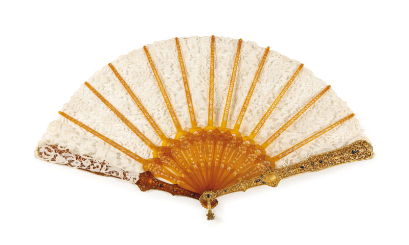 Lotto 36, Ventaglio in tartaruga bionda, pizzo e oro, Firenze, orafo Marchesini, circa 1890mostre finemente lavorate in oro con decori tratti da repertori storicistici, stecche traforate e pizzo con ornato floreale, completo di scatola in legno e raso. Firmato nelle mostre Marchesini Firenze. Cm 49X26. Scatola, cm 10X50X16. Stima € 2.000 - 3.000 - Wannenes 