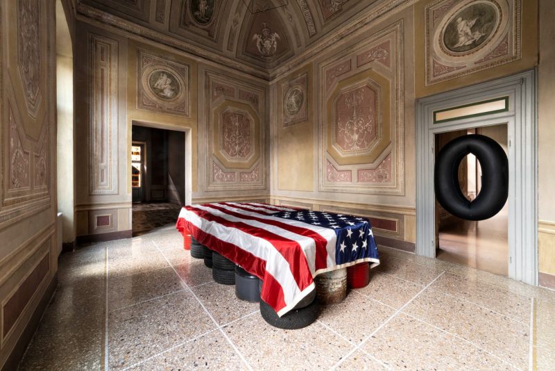 Paolo Canevari, Landscape, 2005, bidoni d’olio, pneumatici, bandiera americana, 190x360x90 cm