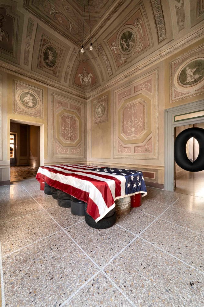 Paolo Canevari, Landscape, 2005, bidoni d’olio, pneumatici, bandiera americana, 190x360x90 cm