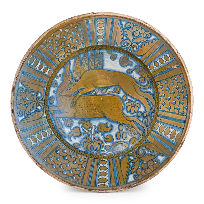 Lotto 326, PIATTO DA PARATA IN MAIOLICA LUSTRATA, FORNACE DI DERUTA, PRIMA METÀ DEL XVI SECOLO decorato con scena di caccia in paesaggio entro un bordo a quartieri; usure, difetti, qualche restauro Etichetta cartacea di collezione, segnatura di collezione manoscritta Alt. cm 7,7, diam. cm 39,5 STIMA 1.800-2.200 euro. Wannenes