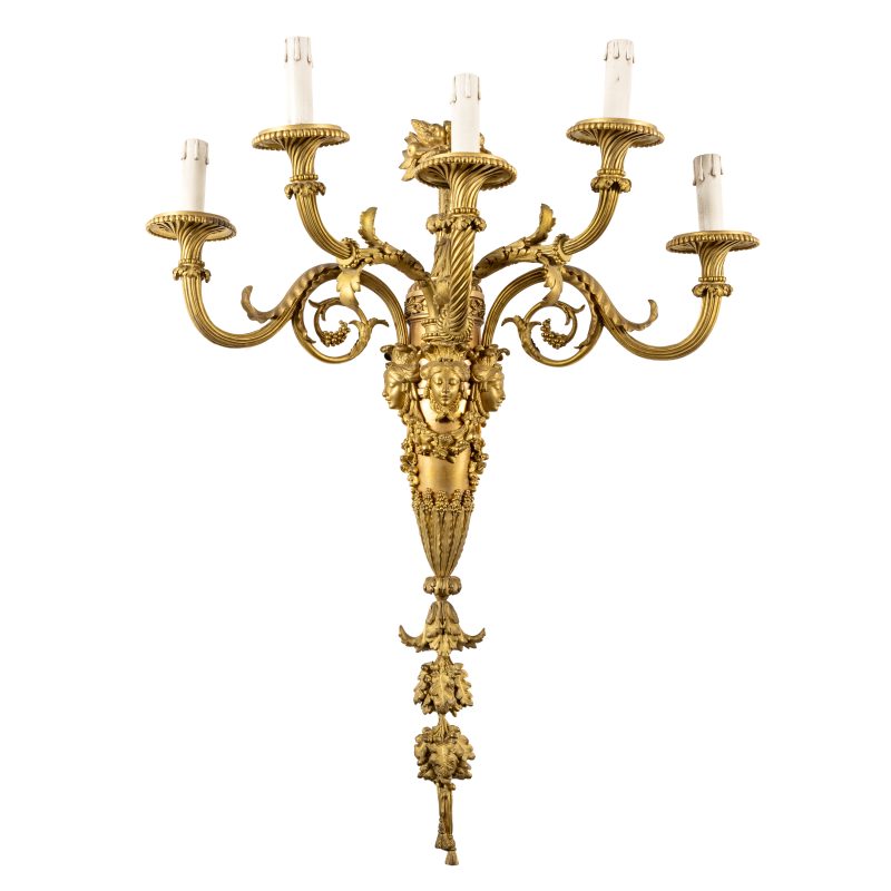 Lotto 5COPPIA DI GRANDI APPLIQUE IN BRONZO DORATO, XIX SECOLO Di gusto neoclassico, ornati da fitto decoro naturalistico e teste muliebri, cinque braccia a cornucopia e vaso fiorito nella sommità; difetti, minori graffi e bruniture, alcune parti da fissare, elettrificati non funzionanti. Cm 79X58X33. Aggiudicazione: € 5.775 Wannenes 